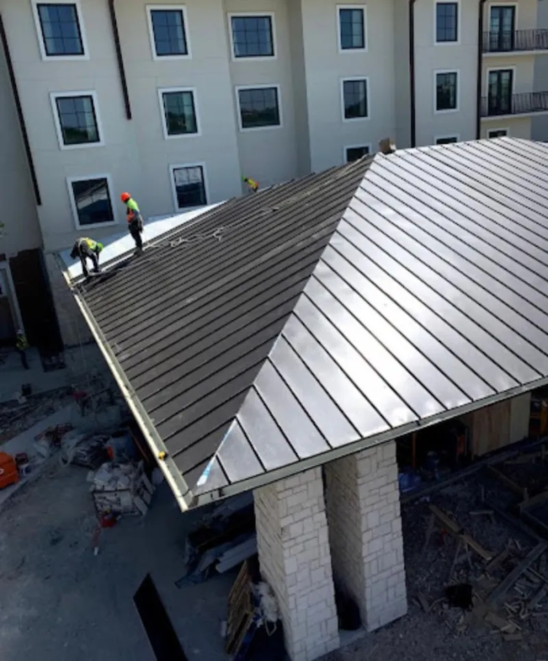 Crew installing standing seam metal roof panels on a commercial project in Lindenwold